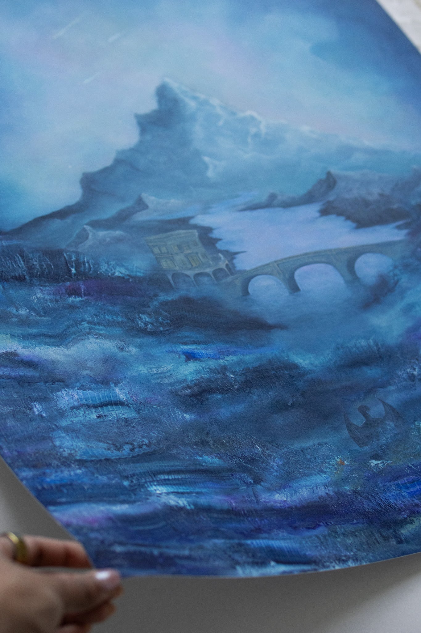 Artistic depiction of a castle on an island with a bridge, rendered in blue tones.